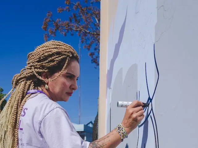Mari Vilhosa desenhando linhas do mural