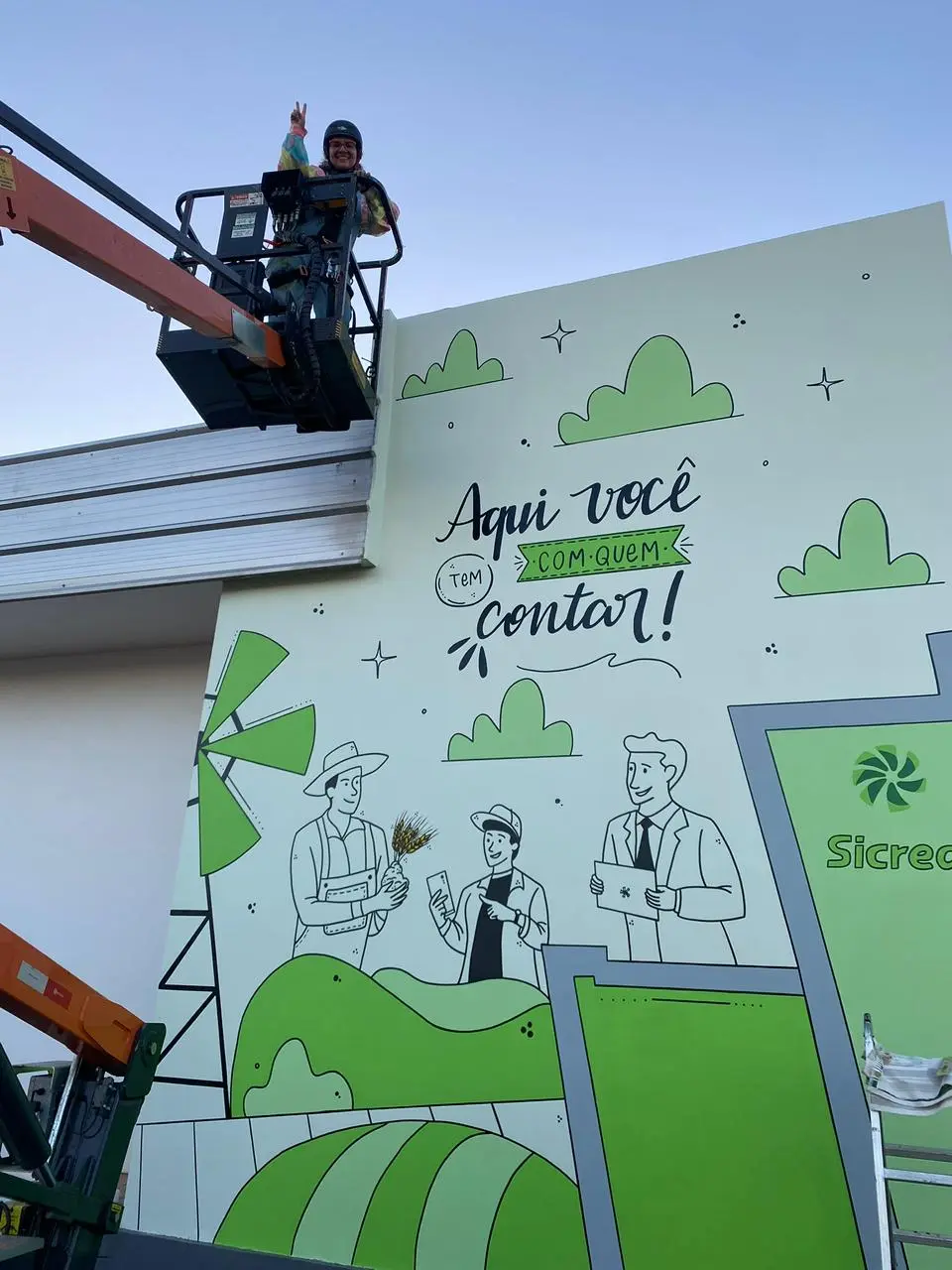 Mari Vilhosa junto ao mural criado para o Sicredi